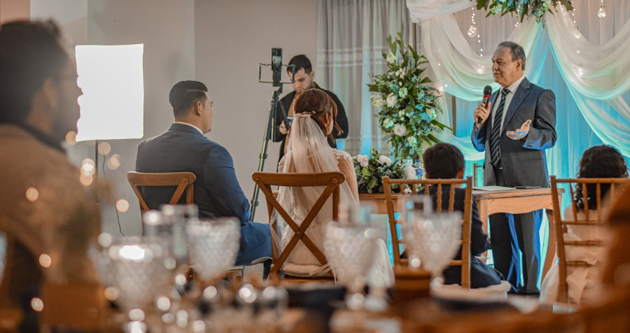 Host giving a speech at a wedding reception with the couple seated nearby
