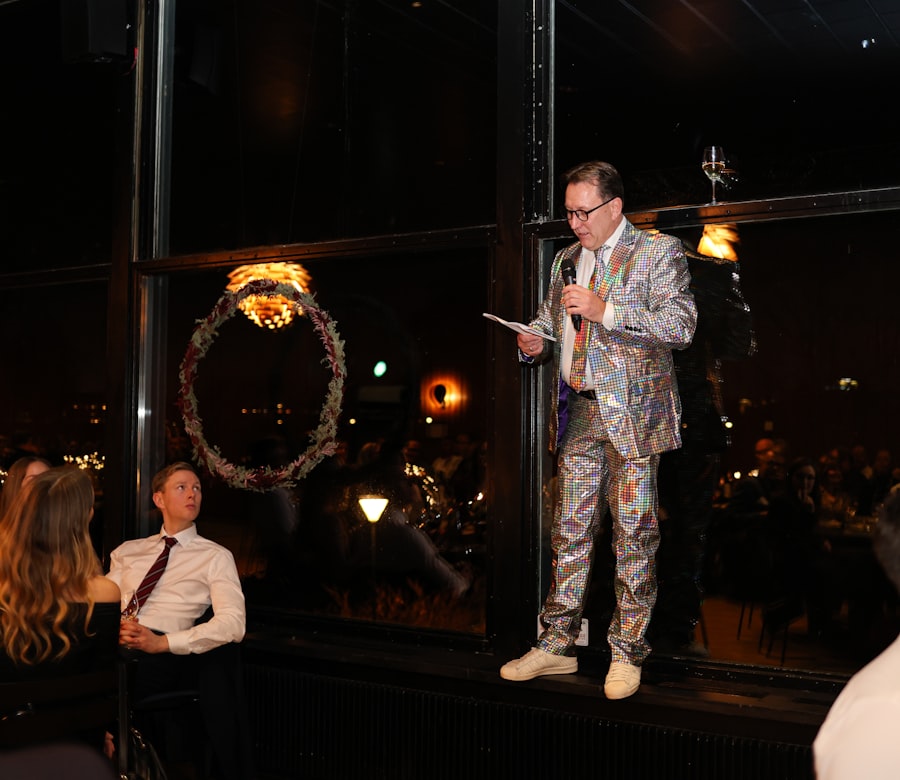 Host in a sparkly jacket presenting at an evening event