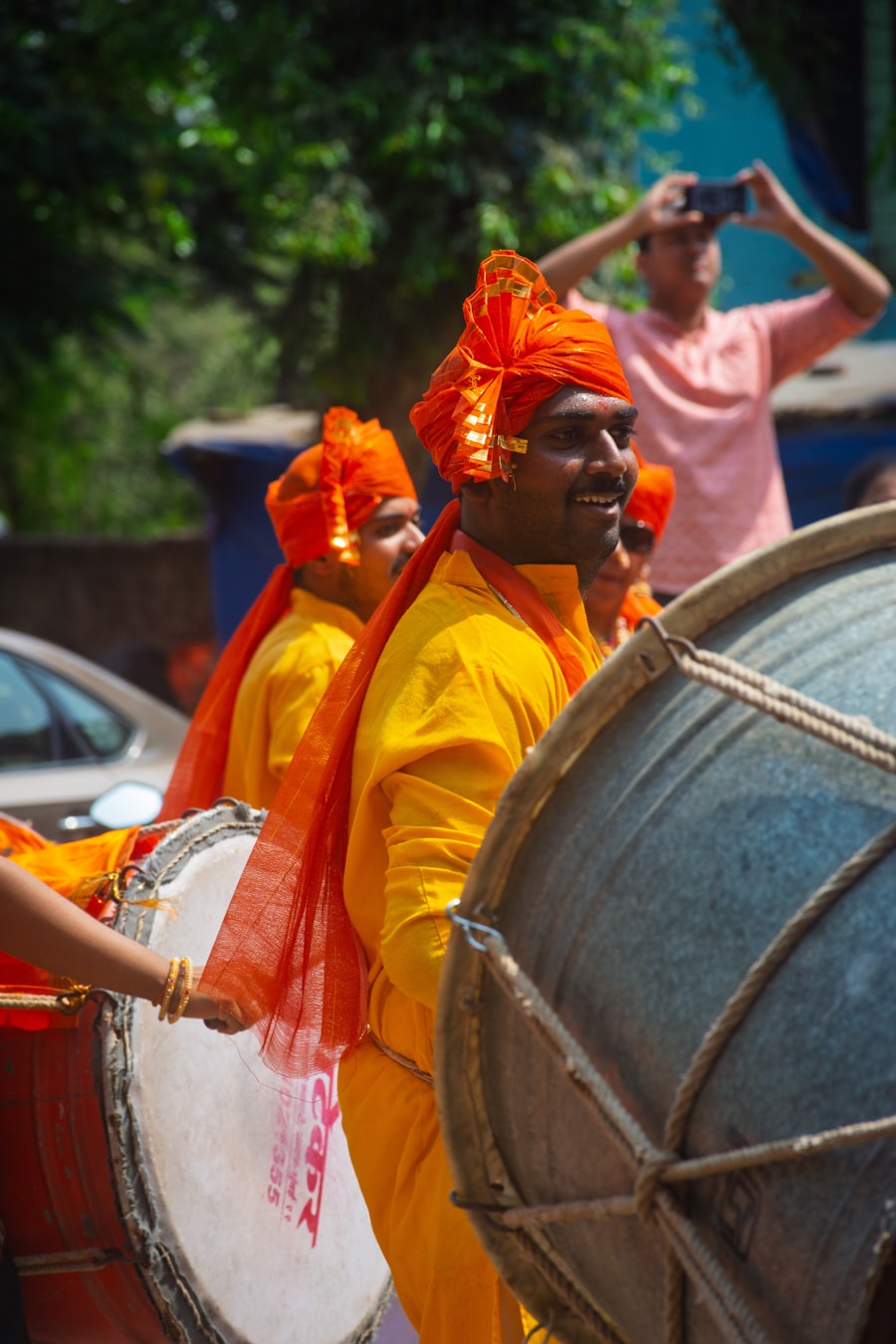 Dhol drummers in orange turbans leading a wedding procession