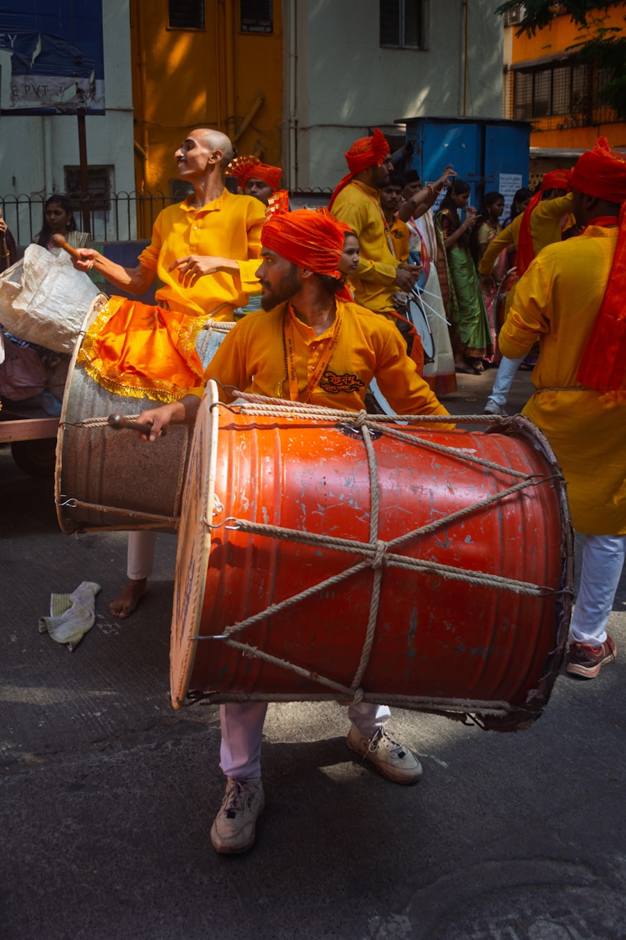 Two drummers playing large dhols in an energetic procession