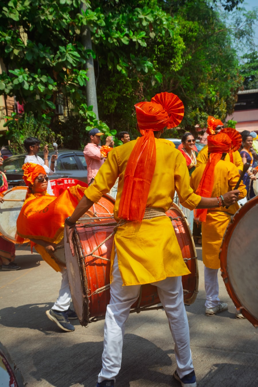 Drummer carrying a large red dhol through the crowd