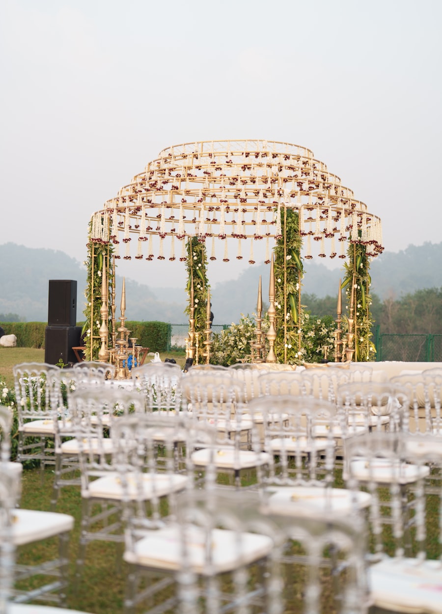 Gold-framed wedding mandap with hanging florals and clear chairs