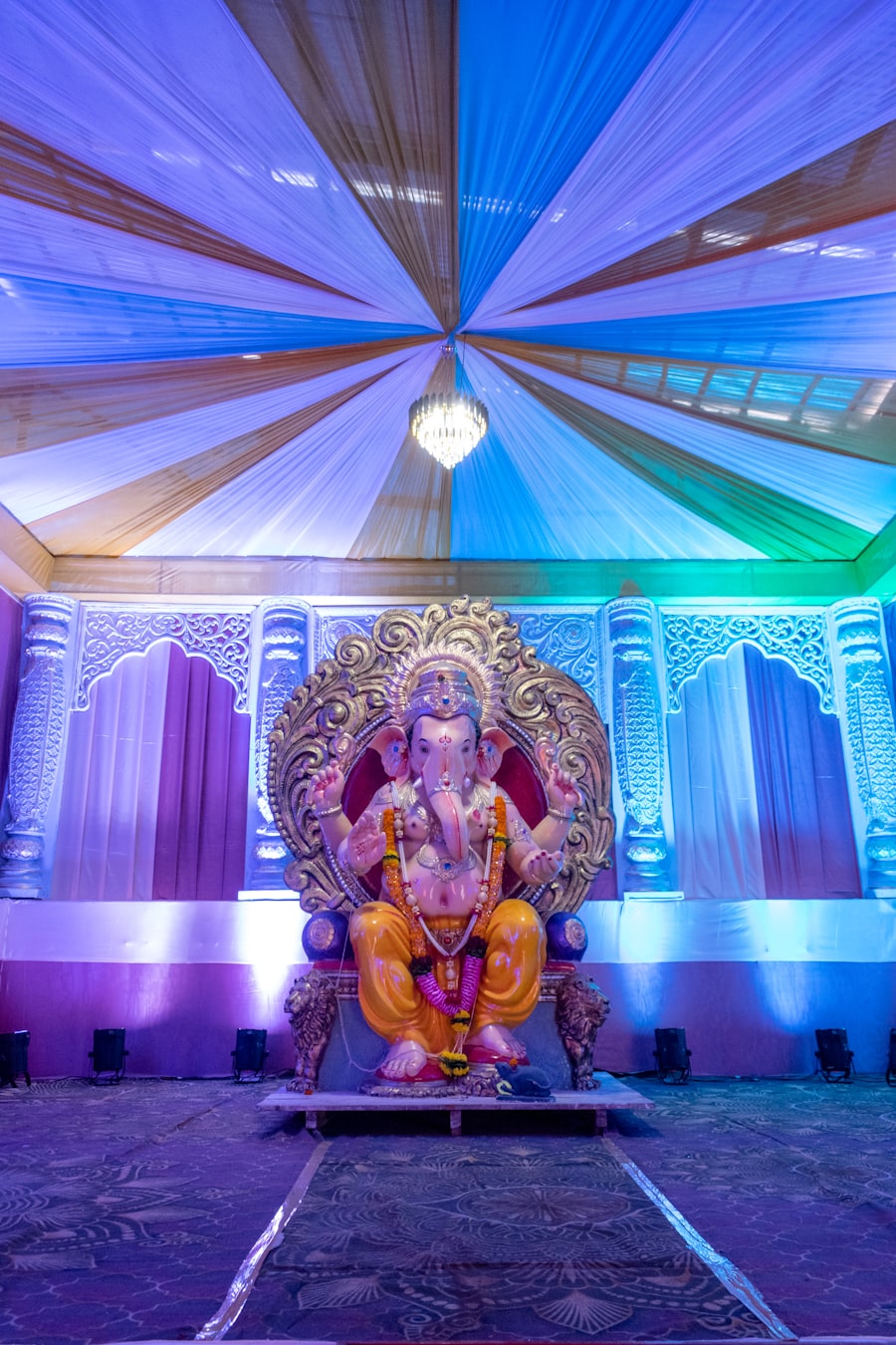 Ganesh idol decorated stage with colorful draped canopy