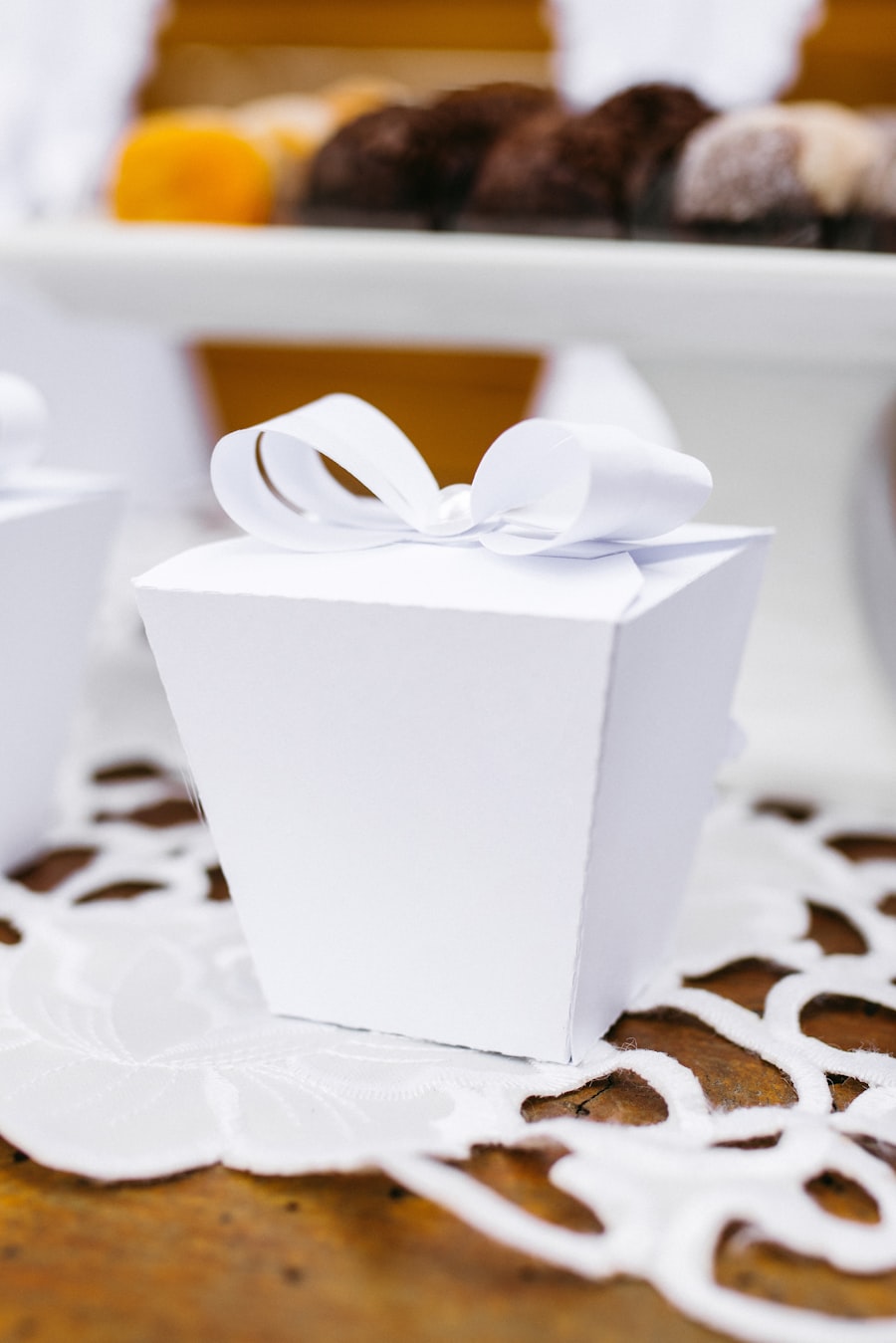 White wedding favor box with bow beside a dessert table