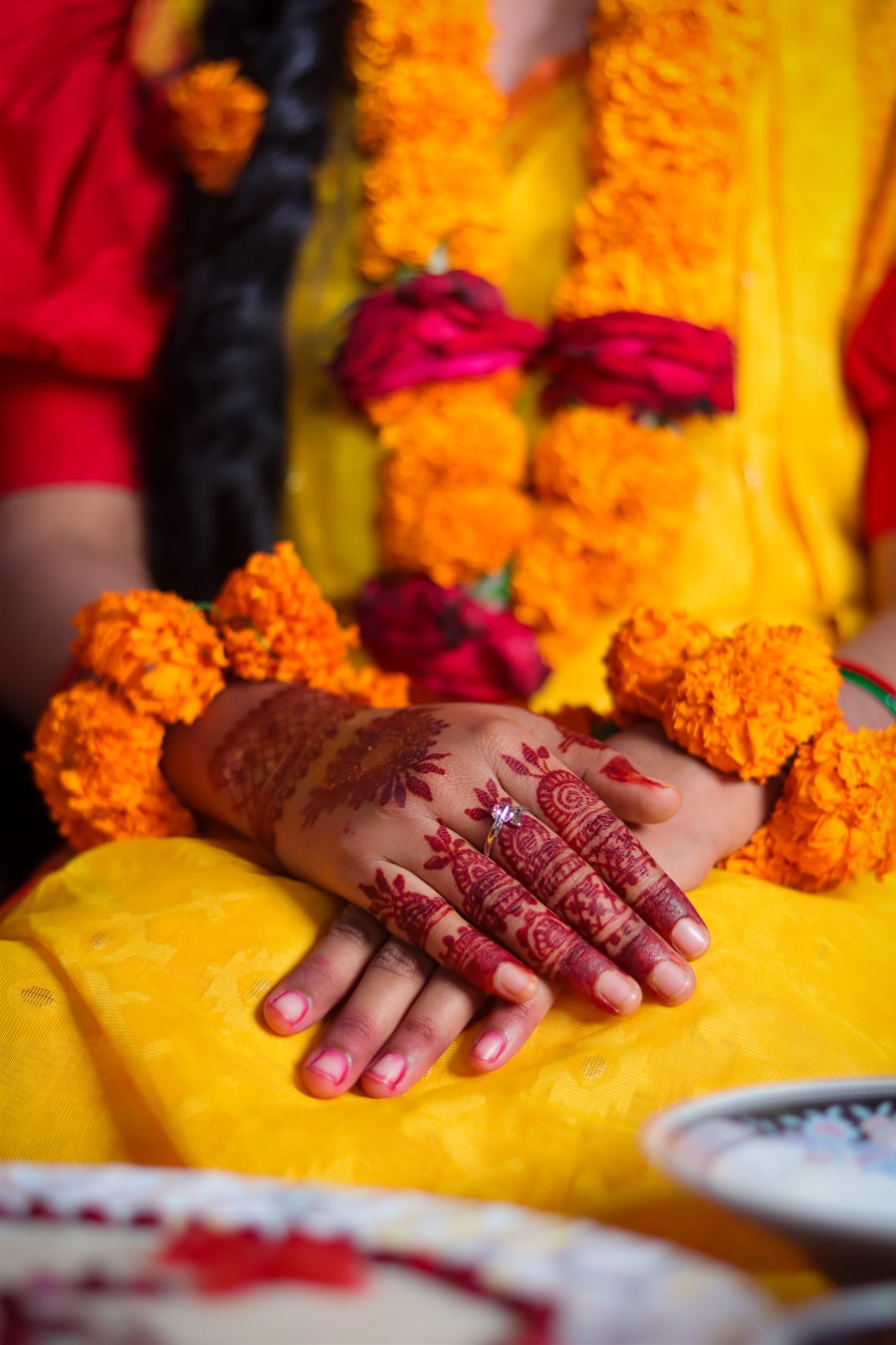 Bride's hennaed hands resting among marigold garlands