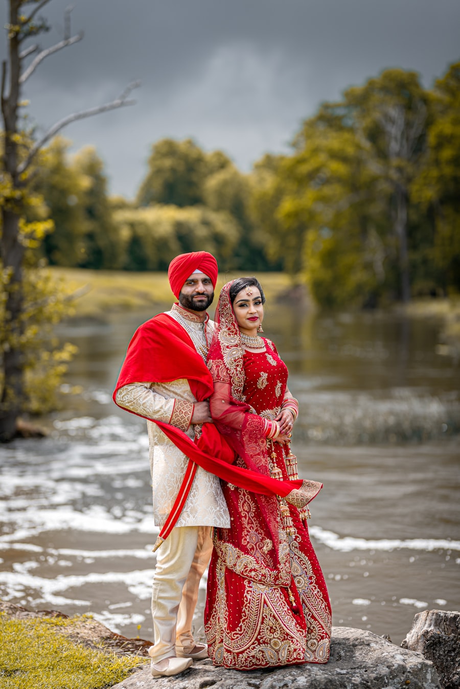 Couple in traditional red wedding attire posing by a river