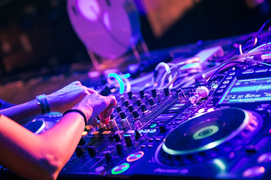Close-up of hands adjusting a DJ mixer under neon light